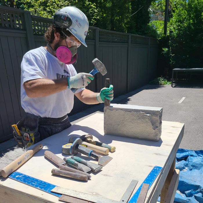 mason hand chiseling natural stone